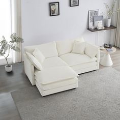 a living room with a large white sectional couch and rug on top of the floor