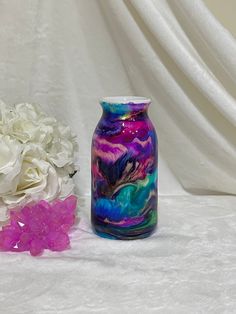 two vases sitting next to each other on a white tablecloth with flowers in the background