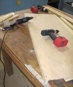 tools are sitting on top of plywood being worked on by an electric screwdriver