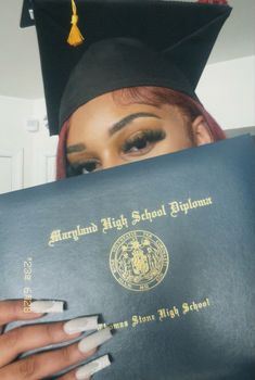 a woman wearing a graduation cap and gown holding up a book with the words, michigan high school diploma written on it