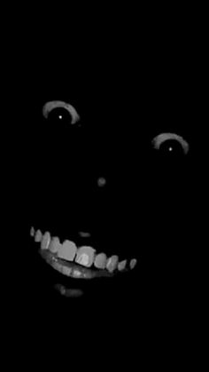 a black and white photo of a smiling child's face in the dark with teeth