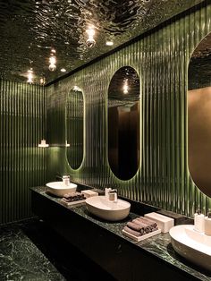 a bathroom with two sinks, mirrors and lights on the wall above them is green