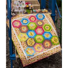 a colorful quilt on a blue chair in front of some flowers and other things outside