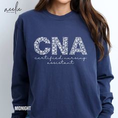 Cute all-white flower designs decorate big CNA letters on this long-sleeved Comfort Colors tee designed to keep you comfortable during those long shifts while showcasing your passion for your profession a Certified Nursing Assistant. Made with 100% ring-spun cotton, these personalized long-sleeve shirts come packed with softness and style. Each tee features garment-dyed fabric and comes with a relaxed fit for total comfort in any casual setting. Add your designs and create an instant wardrobe fa Long Sleeve Cotton T-shirt With Floral Print, Blue Long Sleeve T-shirt With Floral Print, Certified Nursing Assistant, Nursing Assistant, Flower Letters, Comfort Colors Tee, Dyed Fabric, White Flower, Tee Design