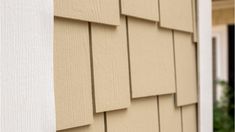 the side of a house that has siding on it and is tan with white trim