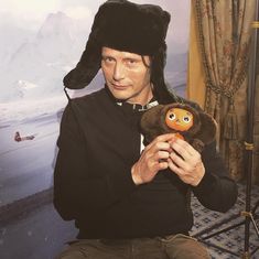 a man holding a teddy bear wearing a hat