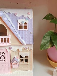 a pink doll house next to a potted plant