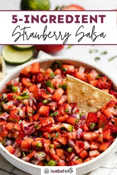 strawberry salsa in a bowl with tortilla chips and limes on the side