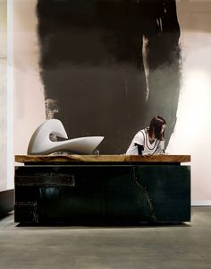 a woman sitting at a desk in front of a black and white painting on the wall