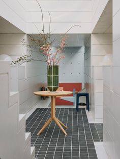 a vase with flowers on top of a table in a room filled with white walls