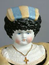 a figurine of a woman wearing a blue and yellow hat with a cross on it