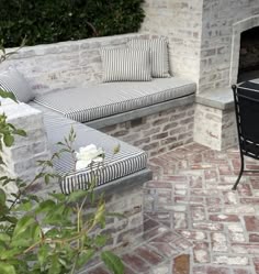 an outdoor fireplace and seating area with brick walls