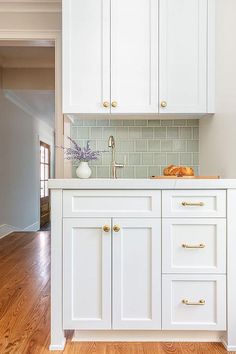 a kitchen with white cabinets and wood floors