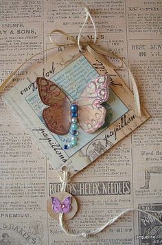 a close up of a butterfly on a piece of paper with beads and string attached to it