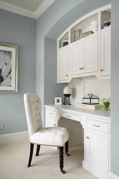 a white chair sitting in front of a desk with drawers and cabinets on top of it