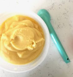 a small bowl filled with food next to a green plastic spoon on a white counter