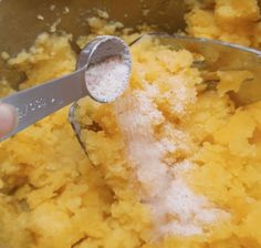 a person using a spoon to mix food in a mixing bowl with sugar on top