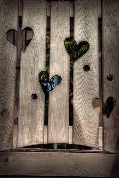 a wooden fence with hearts cut out of it and the words written in two languages