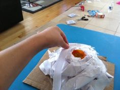 a person is picking up some food from a bag on the floor with other items scattered around