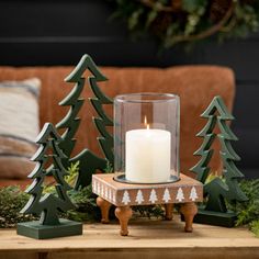 a candle is sitting on a table next to christmas trees