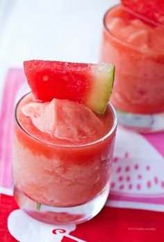 a glass filled with ice and watermelon slices next to a pink striped straw