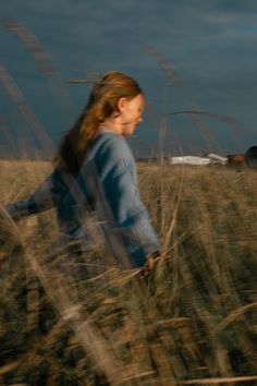 a woman is walking through the tall grass