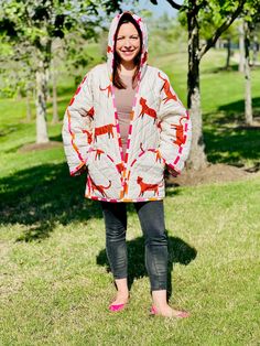 a woman standing in the grass wearing a jacket with an animal print on it and pink shoes