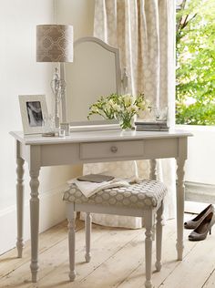 a dining room table with chairs and a vase on the end shelf in front of it