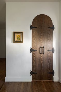 an empty room with a wooden door in the center and framed artwork on the wall