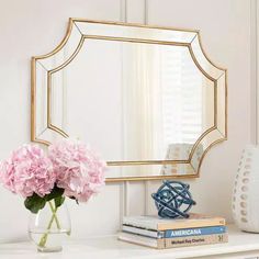 a vase with pink flowers sitting on top of a white table next to a mirror