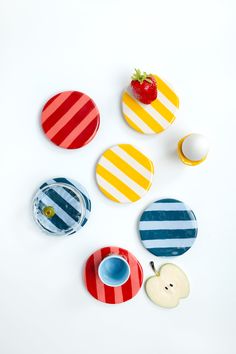 four plates with different designs on them sitting next to an egg, strawberry and cupcake