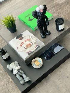 a coffee table with various items on it and a book in the background, sitting next to a potted plant