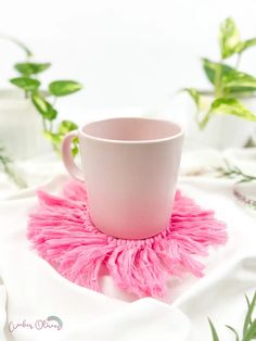 a pink coffee cup sitting on top of a white saucer covered in fluffy pink pom - poms