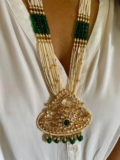 All our pieces are in stock and will be dispatched within 24 to 48 hours of order. Orders received during the weekend will be dispatched on Monday. The white and green beads strings on both sides of an elegant Kundan pendant make it a statement wedding necklace. One of our favorite picks for the wedding season ❤️ Dimensions Weight of the necklace: 78 grams Drop Length of the necklace: 12 inches Height of pendant: 3.5 inches Width of pendant: 3 inches Weight of earrings is 46 g per pair. Length o Traditional White Jeweled Necklace, Handmade Green Bridal Necklace For Wedding, Gold Pendant Beaded Necklaces For Wedding, Traditional Jewelry With Large Pendant For Celebration, Traditional White Jewelry With Jewels, Ornate Pendant Jewelry For Wedding, Bridal Necklace With Intricate Design For Celebration, Ornate Green Jewelry For Festivals, Green Fusion Bridal Necklace With Intricate Design