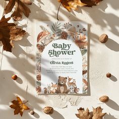 a baby shower book surrounded by leaves and acorns