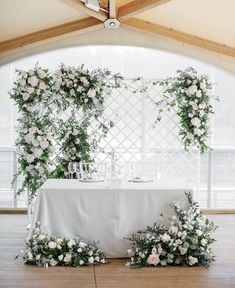 the table is set with white flowers and greenery