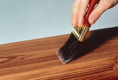 a person holding a paint brush on top of a wooden table