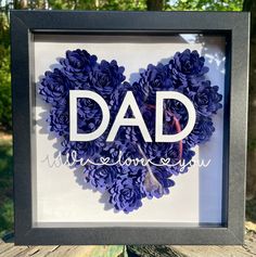 a shadow frame with flowers in the shape of a heart that reads, dad is someone