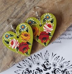 two heart shaped wooden earrings sitting on top of a piece of paper next to a drawing