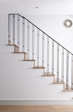 a set of stairs with wooden handrails in a white room next to a light fixture