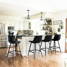 a kitchen with white cabinets and black bar stools