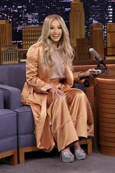 a woman sitting on top of a blue couch in front of a tv screen with a microphone