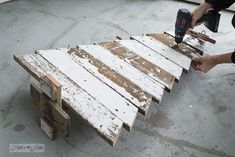 a man sanding down a wooden pallet with a power drill on top of it