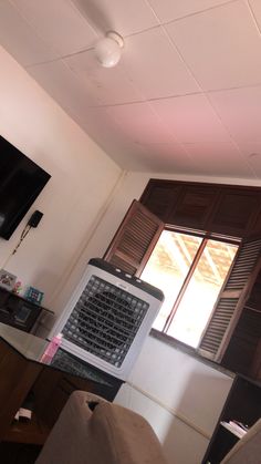 an air conditioner sitting in the corner of a living room next to a window