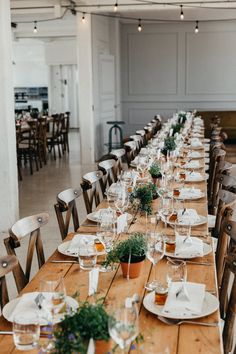 a long wooden table with plates and place settings on it, set for an event