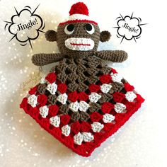 a crocheted sock monkey sitting on top of a red and white blanket