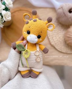 a crocheted giraffe is holding a flower in it's hand