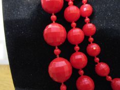 This vintage 1940's necklace has a great chunky Art Deco look and though not Bakelite it has the substantial weight of an early plastic necklace. Beads are faceted and separated by small red spacer beads. Strands are graduated. The bottom strand has 17 mm beads, the middle strand has 12 mm beads and the top strand has 9 mm beads. This necklace is in very good original condition. It's longest strand is 18 inches in length, middle strand is 14 inches and smallest strand is 12 inches. The necklace Vintage Red Faceted Beads Jewelry, Retro Red Necklace For Party, Vintage Beaded Necklace With Large Beads For Party, Vintage Party Beaded Necklaces With Large Beads, Vintage Party Beaded Necklace With Large Beads, Vintage Large Beads Necklaces For Party, Retro Red Beaded Necklace, Vintage Necklaces With Large Beads For Party, Vintage Red Beaded Necklaces For Party