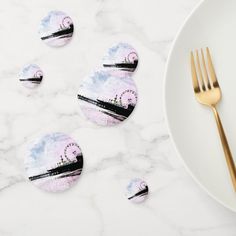 four coasters sitting on top of a white plate next to a fork and knife