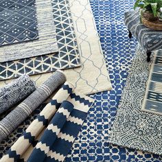 blue and white rugs are laid out on the floor in front of a potted plant